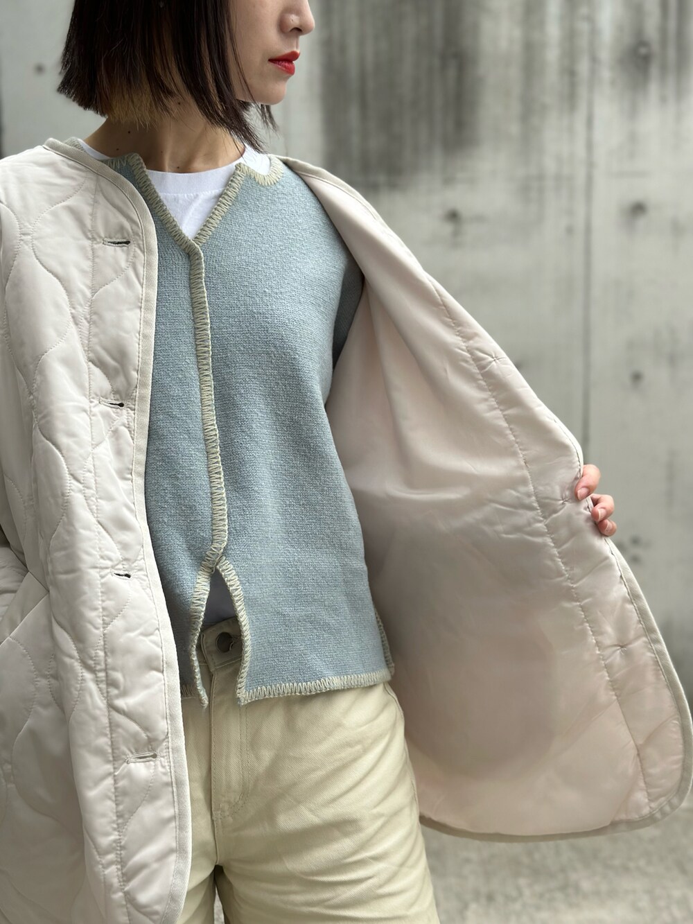 ホワイト系のノーカラージャケット、ブラウン系のベスト、ブルー系のニット/セーターを着用したレディースの冬コーディネートの5枚目の写真