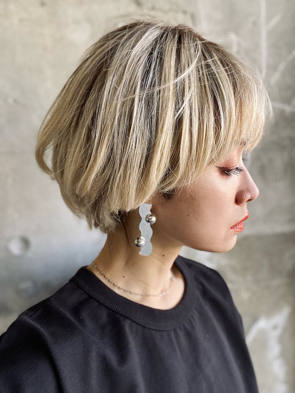 シルバー系のスカート、ブラック系のブーツ、ブラック系のTシャツ/カットソーを着用したレディースの春コーディネートの4枚目の写真