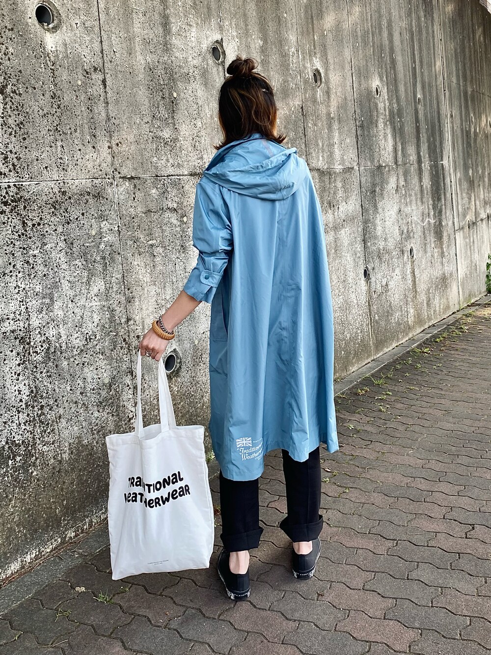 ホワイト系のトートバッグ、ホワイト系のTシャツ/カットソー、ブラック系のスラックスを着用したレディースの春コーディネートの3枚目の写真