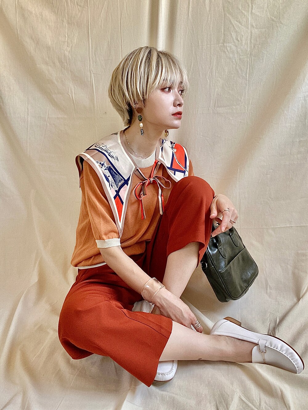 オレンジ系のニット/セーター、ホワイト系のサンダル、ホワイト系のサロペット/オーバーオールを着用したレディースの春コーディネートの2枚目の写真