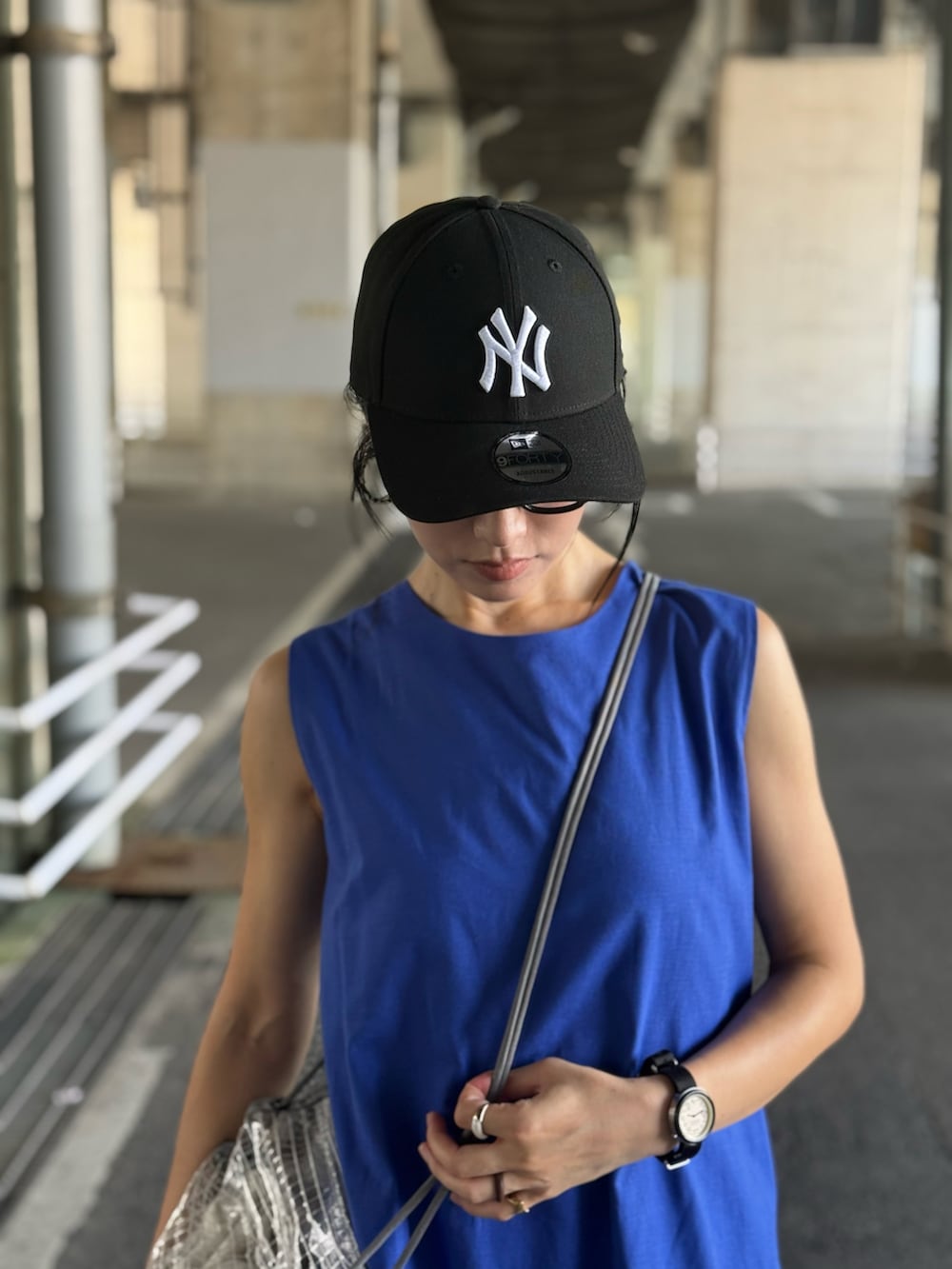 ブルー系のワンピース、ベージュ系のスニーカー、ブラック系のキャップを着用したレディースの夏コーディネートの2枚目の写真