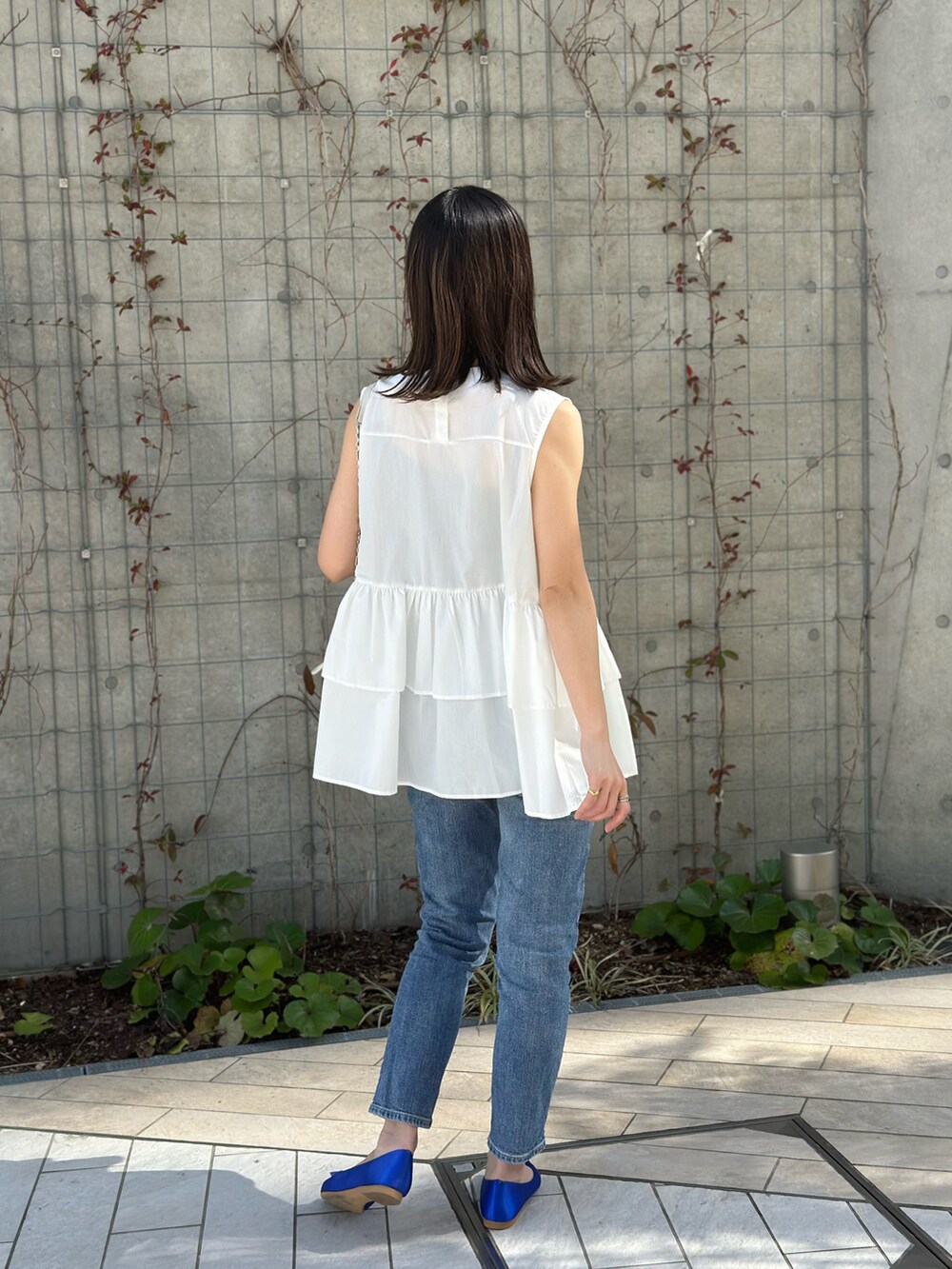 ホワイト系のチュニック、ブルー系のパンプス、その他のショルダーバッグを着用したレディースの夏コーディネートの4枚目の写真