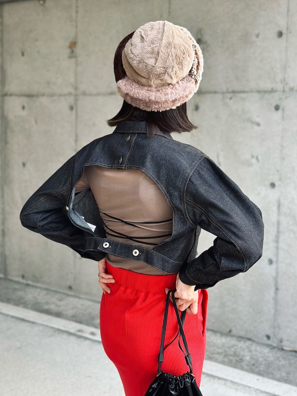 ブラック系のデニムジャケット、レッド系のスカート、ブラック系のハンドバッグを着用したレディースの秋コーディネートの2枚目の写真