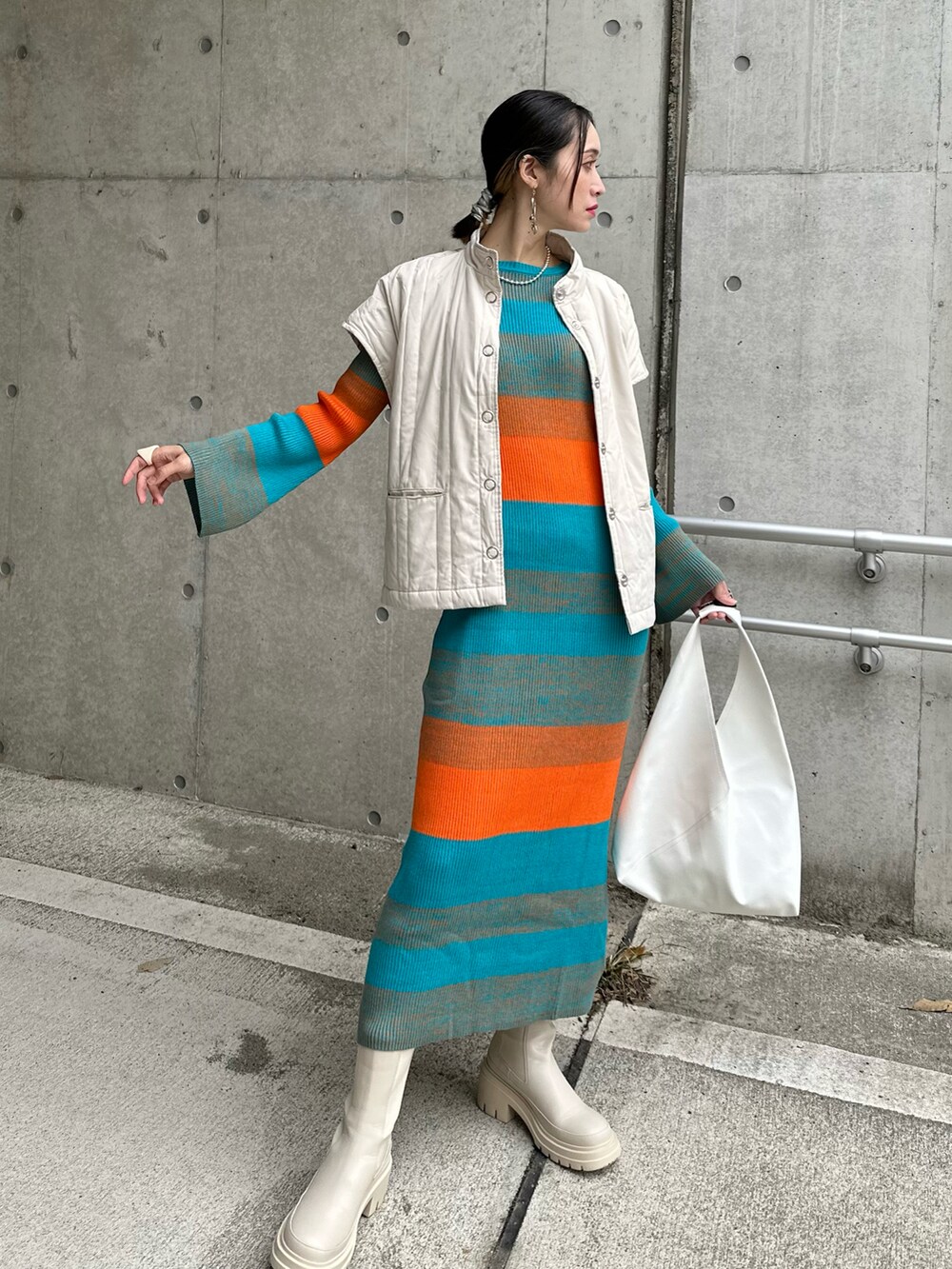 ブルー系のワンピース、ホワイト系のダウンベスト、ベージュ系のブーツを着用したレディースの秋コーディネートの3枚目の写真