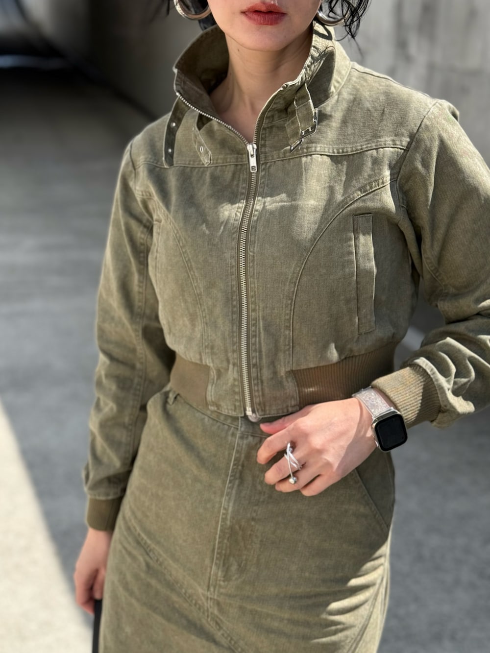 グリーン系のブルゾン、グリーン系のスカート、ブラック系のハンドバッグを着用したレディースの春コーディネートの2枚目の写真