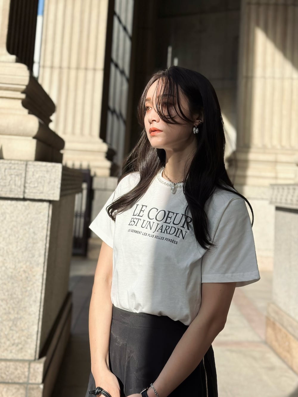 ホワイト系のTシャツ/カットソー、シルバー系のサンダル、ブラック系のスカートを着用したレディースの春コーディネートの3枚目の写真