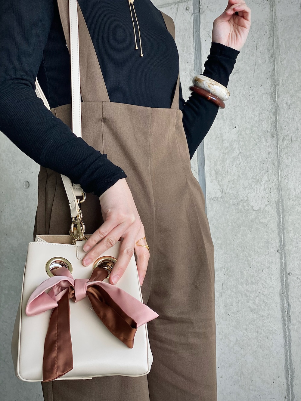 ブラウン系のサロペット/オーバーオール、ブラック系のTシャツ/カットソー、ブラック系のブーツを着用したレディースの冬コーディネートの3枚目の写真