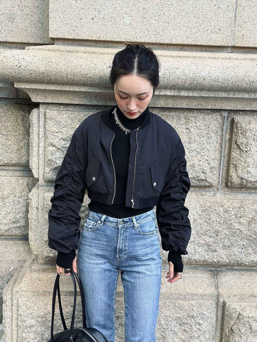 ブラック系のブルゾン、レッド系のブーツ、ブラック系のボストンバッグを着用したレディースの秋コーディネートの3枚目の写真