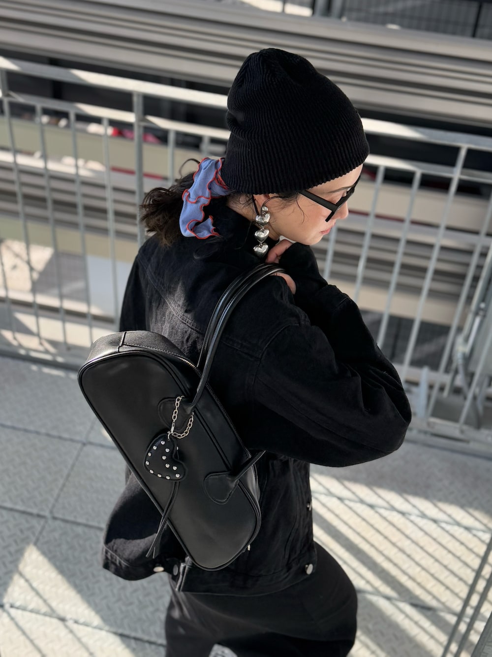 ブラック系のデニムジャケット、ブラック系のワンピース、ブラック系のボストンバッグを着用したレディースの冬コーディネートの4枚目の写真