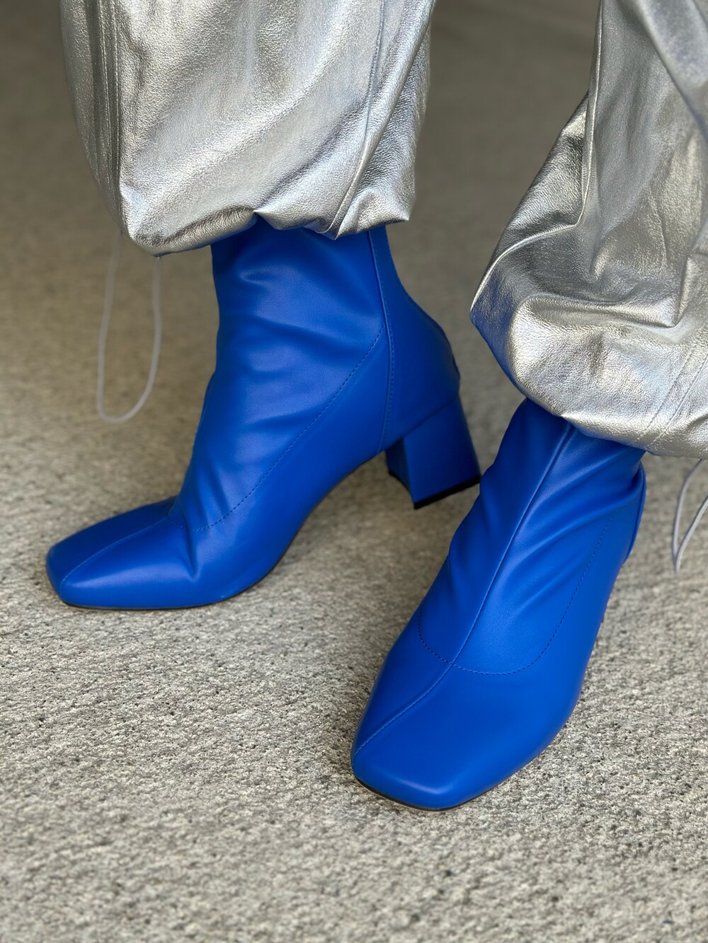 ブラック系のハンドバッグ、シルバー系のその他パンツ、ブルー系のチェスターコートを着用したレディースの冬コーディネートの3枚目の写真