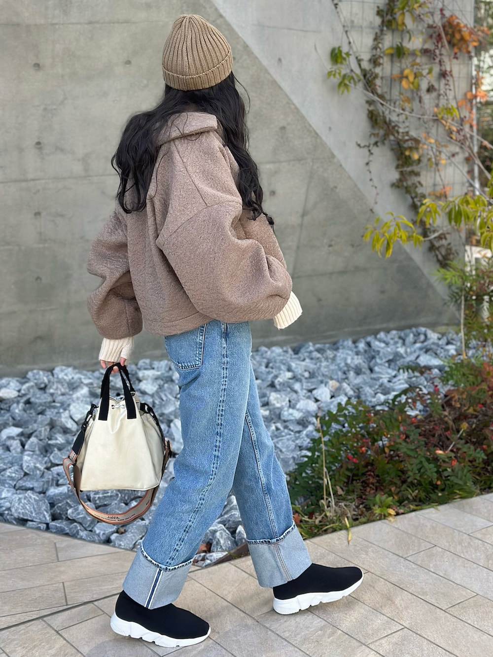 ベージュ系のブルゾン、オレンジ系のニット/セーター、ホワイト系のショルダーバッグを着用したレディースの冬コーディネートの3枚目の写真