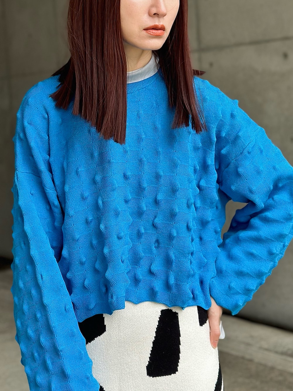 ブルー系のニット/セーター、ホワイト系のスカート、ベージュ系のTシャツ/カットソーを着用したレディースの冬コーディネートの3枚目の写真