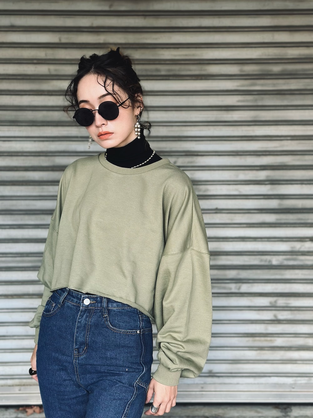 グリーン系のニット/セーター、ブルー系のデニムパンツ、ブラック系のブーツを着用したレディースの冬コーディネートの2枚目の写真