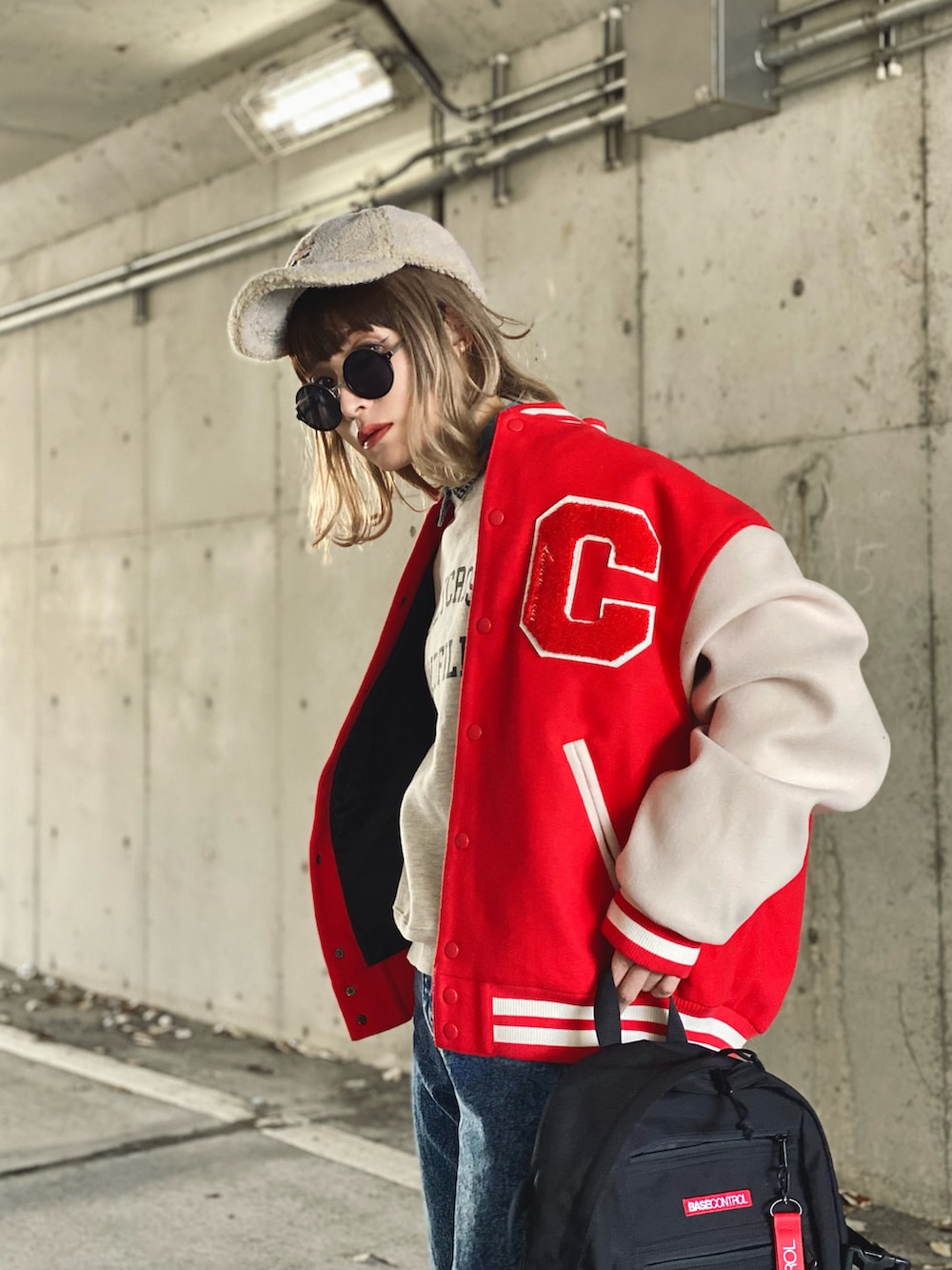 レッド系のスタジャン、ベージュ系のスウェット、ブルー系のデニムパンツを着用したレディースの冬コーディネートの2枚目の写真