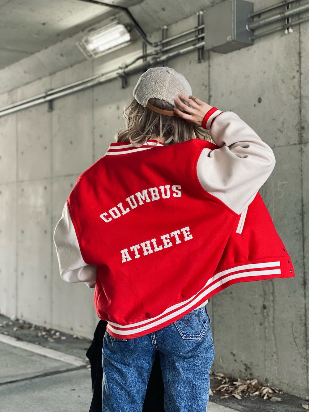 レッド系のスタジャン、ベージュ系のスウェット、ブルー系のデニムパンツを着用したレディースの冬コーディネートの3枚目の写真