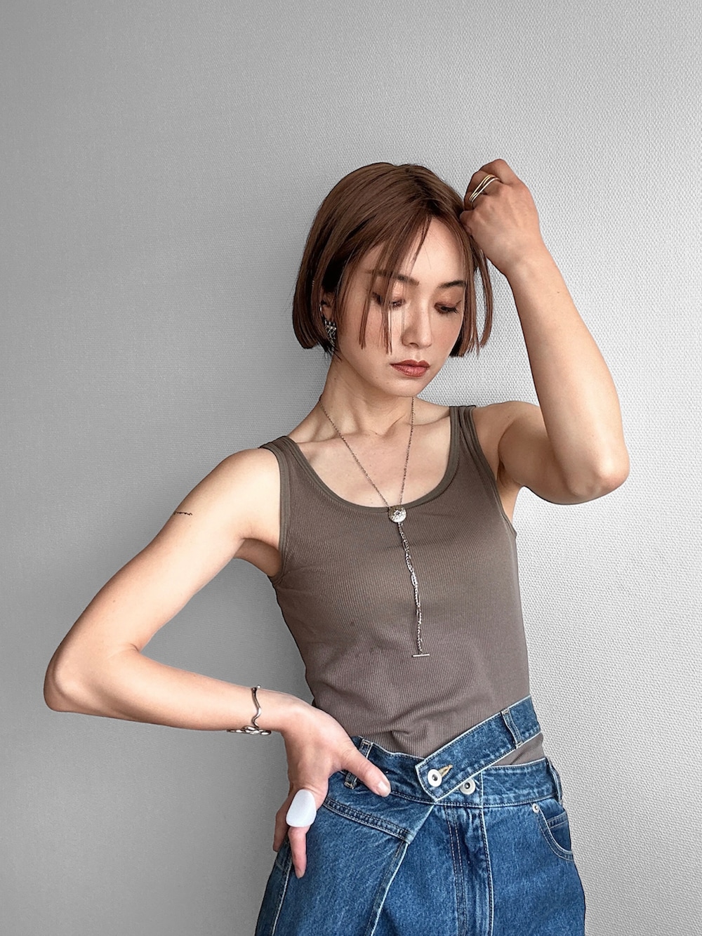 グリーン系のタンクトップ、ブルー系のデニムパンツ、ブラック系のその他アウターを着用したレディースの春コーディネートの2枚目の写真