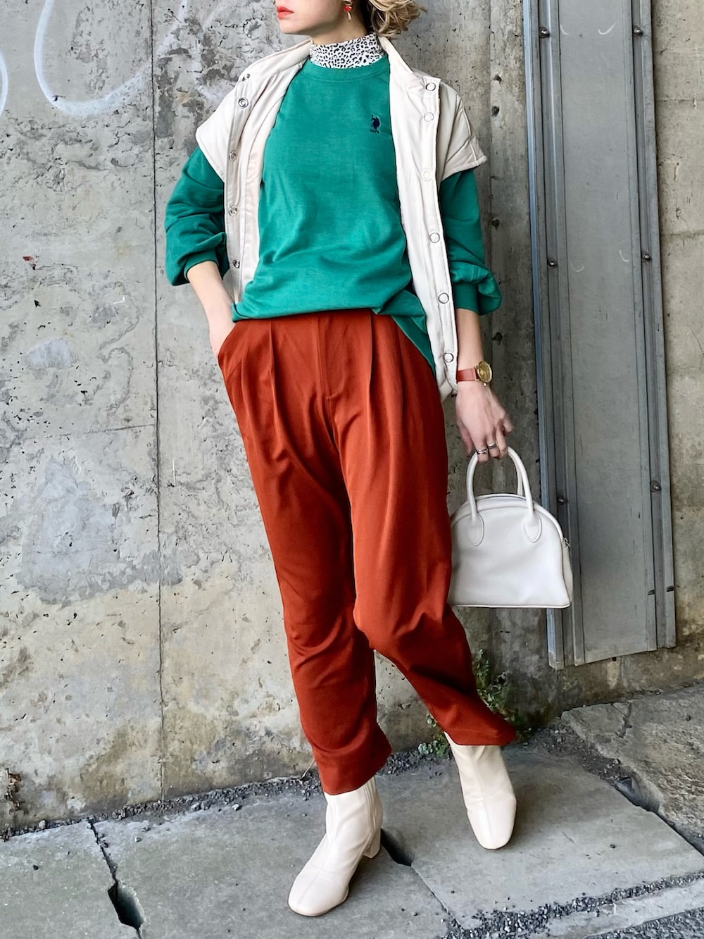 グリーン系のスウェット、ホワイト系のダウンベスト、ベージュ系のボストンバッグを着用したレディースの冬コーディネートの5枚目の写真