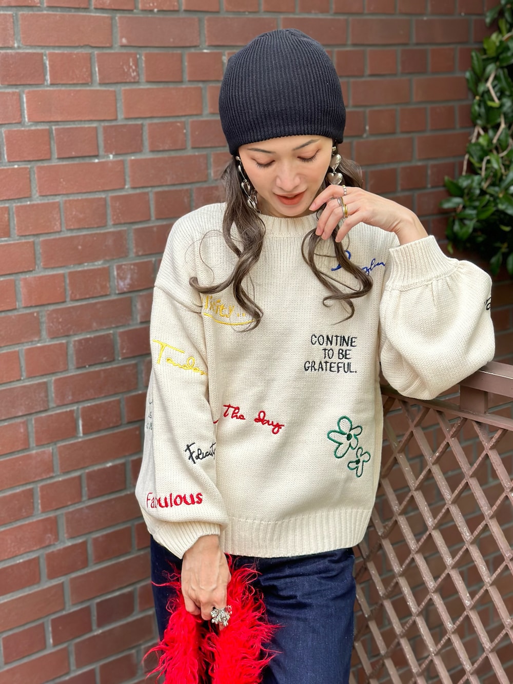 ホワイト系のニット/セーター、ブルー系のデニムパンツ、レッド系のトートバッグを着用したレディースの秋コーディネートの2枚目の写真