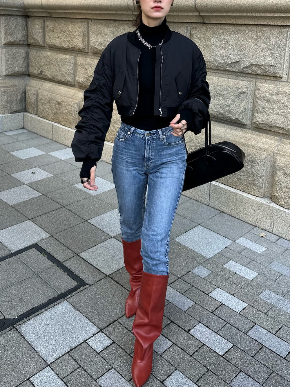 ブラック系のブルゾン、レッド系のブーツ、ブラック系のボストンバッグを着用したレディースの秋コーディネートの4枚目の写真