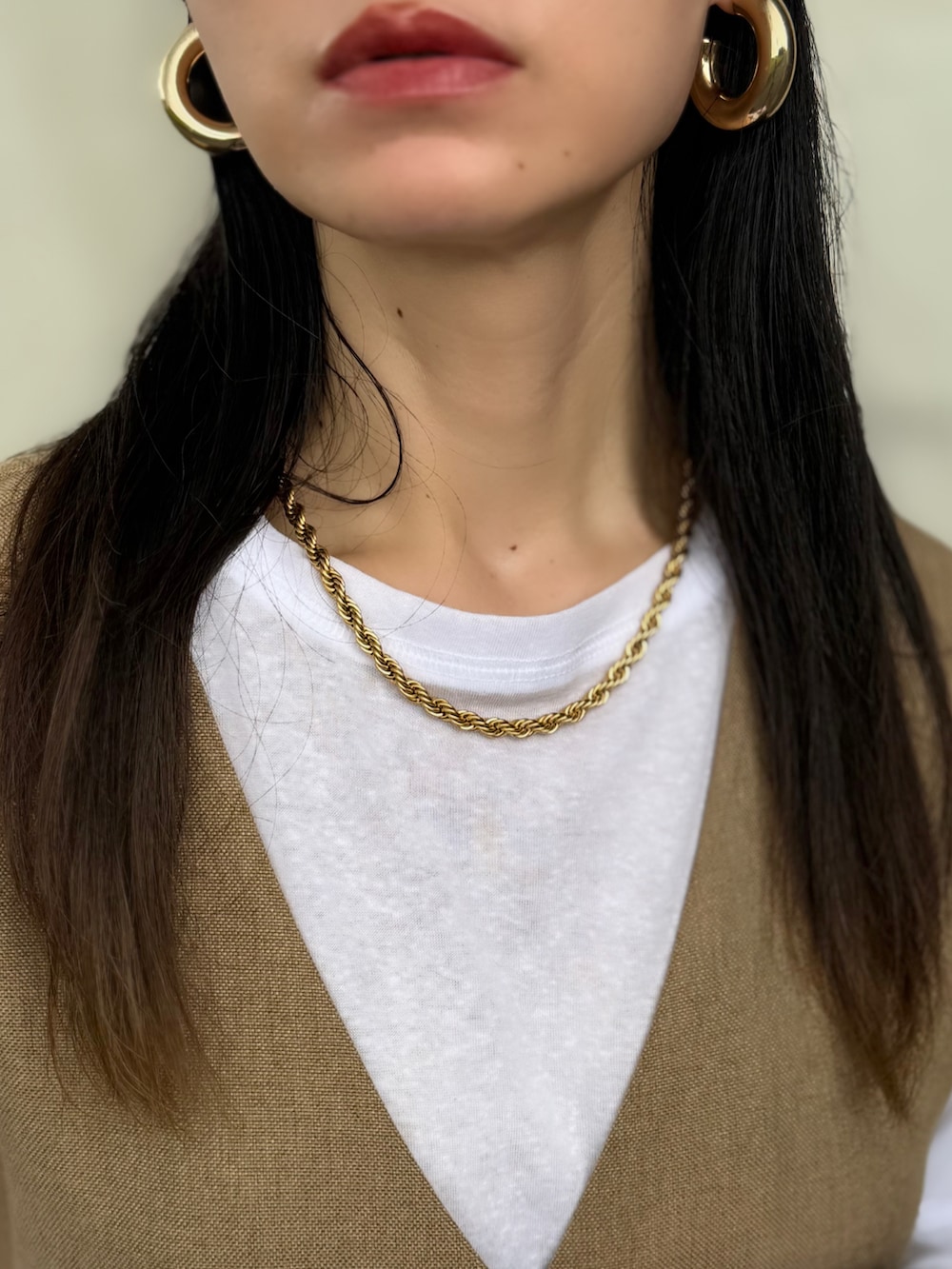 グリーン系のベスト、ホワイト系のTシャツ/カットソー、ベージュ系のスカートを着用したレディースの秋コーディネートの5枚目の写真