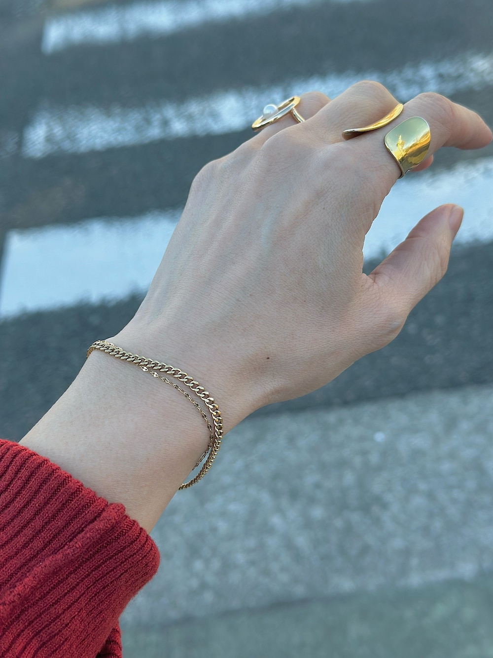 グレー系のステンカラーコート、レッド系のニット/セーター、レッド系のショルダーバッグを着用したレディースの冬コーディネートの3枚目の写真