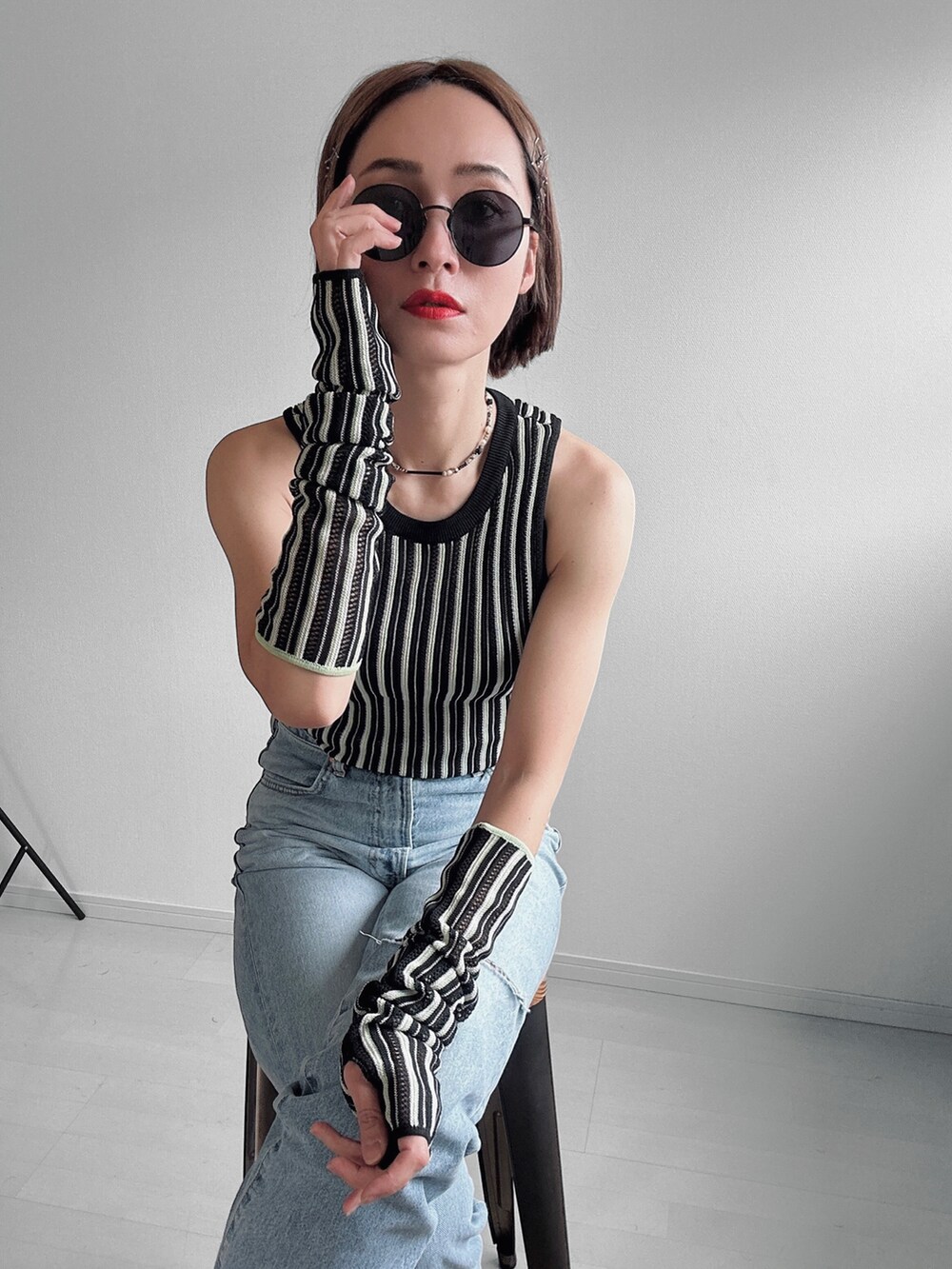 シルバー系のサンダル、ブラック系のニット/セーター、ブルー系のデニムパンツを着用したレディースの春コーディネートの3枚目の写真