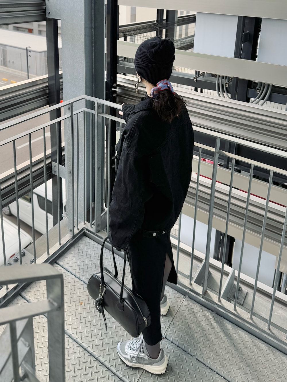 ブラック系のデニムジャケット、ブラック系のワンピース、ブラック系のボストンバッグを着用したレディースの冬コーディネートの5枚目の写真