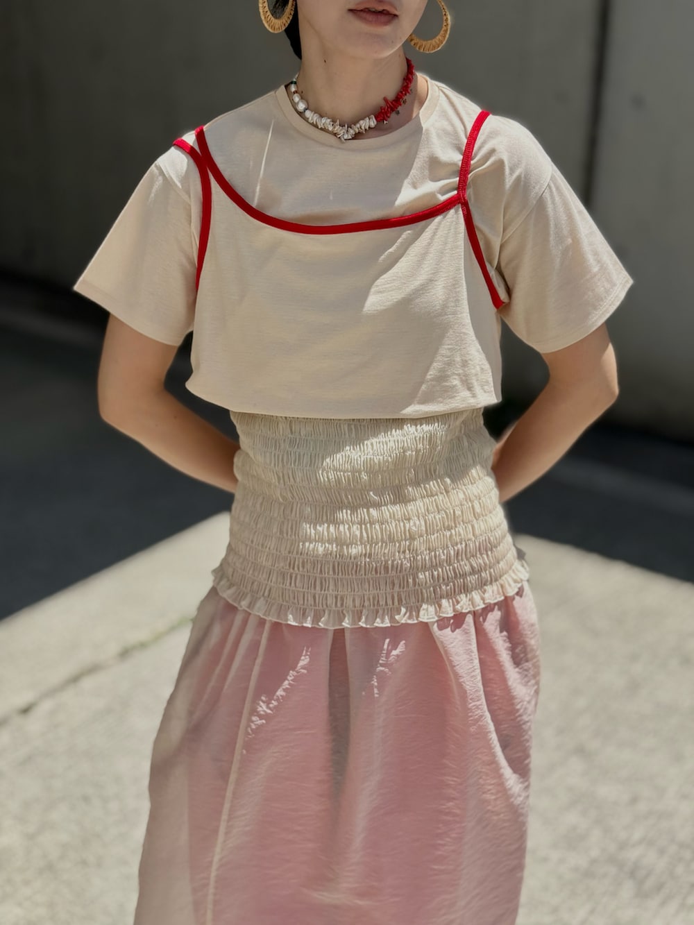 レッド系のショルダーバッグ、ベージュ系のTシャツ/カットソー、ベージュ系のスカートを着用したレディースの夏コーディネートの2枚目の写真