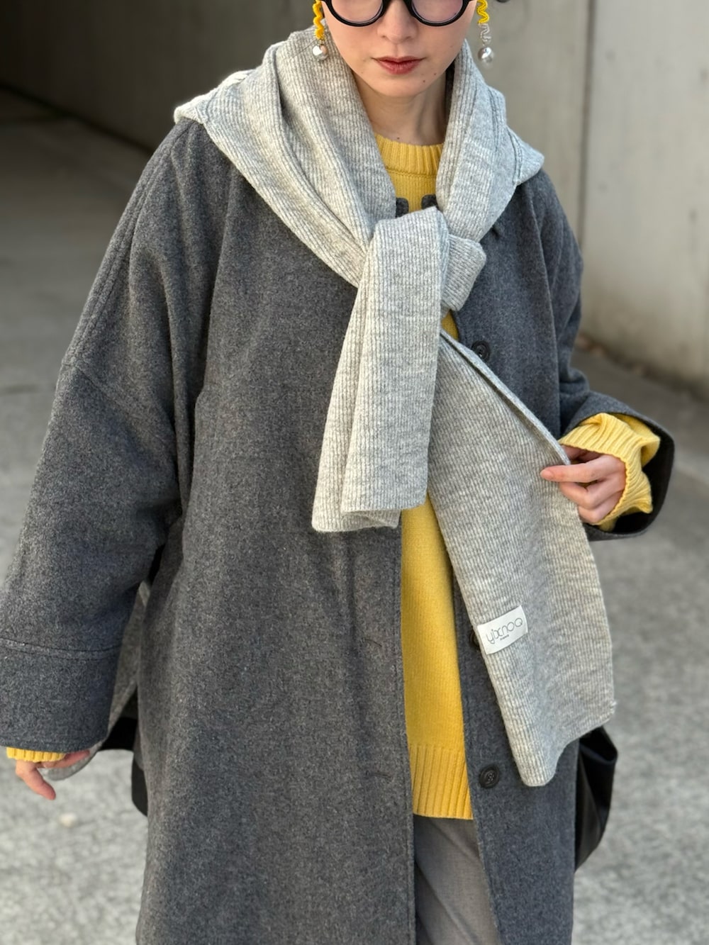 イエロー系のニット/セーター、グレー系のその他アウター、グレー系のスラックスを着用したレディースの春コーディネートの2枚目の写真