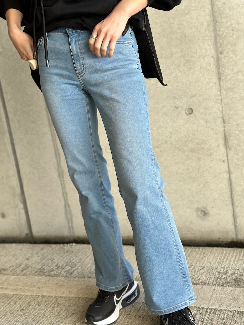 ブルー系のデニムパンツ、ブラック系のショルダーバッグ、ブラック系のスウェットを着用したレディースの春コーディネートの3枚目の写真