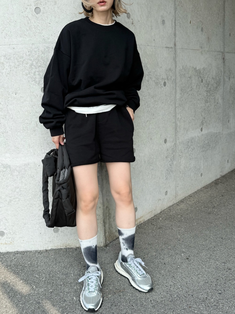 グレー系のスニーカー、グレー系のトートバッグ、ブラック系のセットアップを着用したレディースの秋コーディネートの3枚目の写真