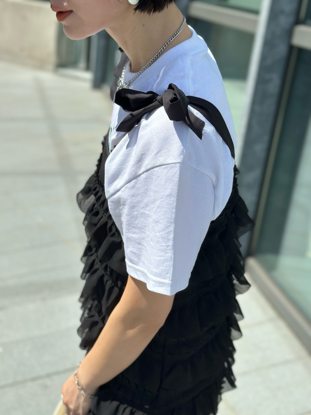 ブラック系のワンピース、ホワイト系のTシャツ/カットソー、ブルー系のデニムパンツを着用したレディースの春コーディネートの4枚目の写真