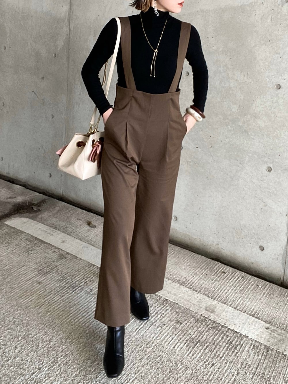 ブラウン系のサロペット/オーバーオール、ブラック系のTシャツ/カットソー、ブラック系のブーツを着用したレディースの冬コーディネートの5枚目の写真