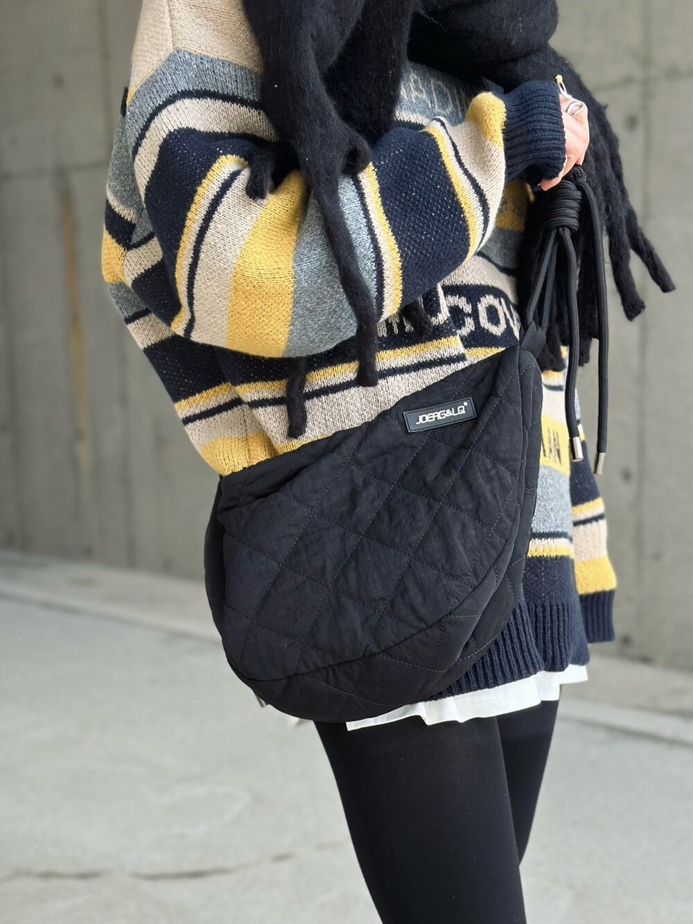 ブルー系のニット/セーター、ブラック系のショルダーバッグ、ブラック系のスニーカーを着用したレディースの冬コーディネートの5枚目の写真