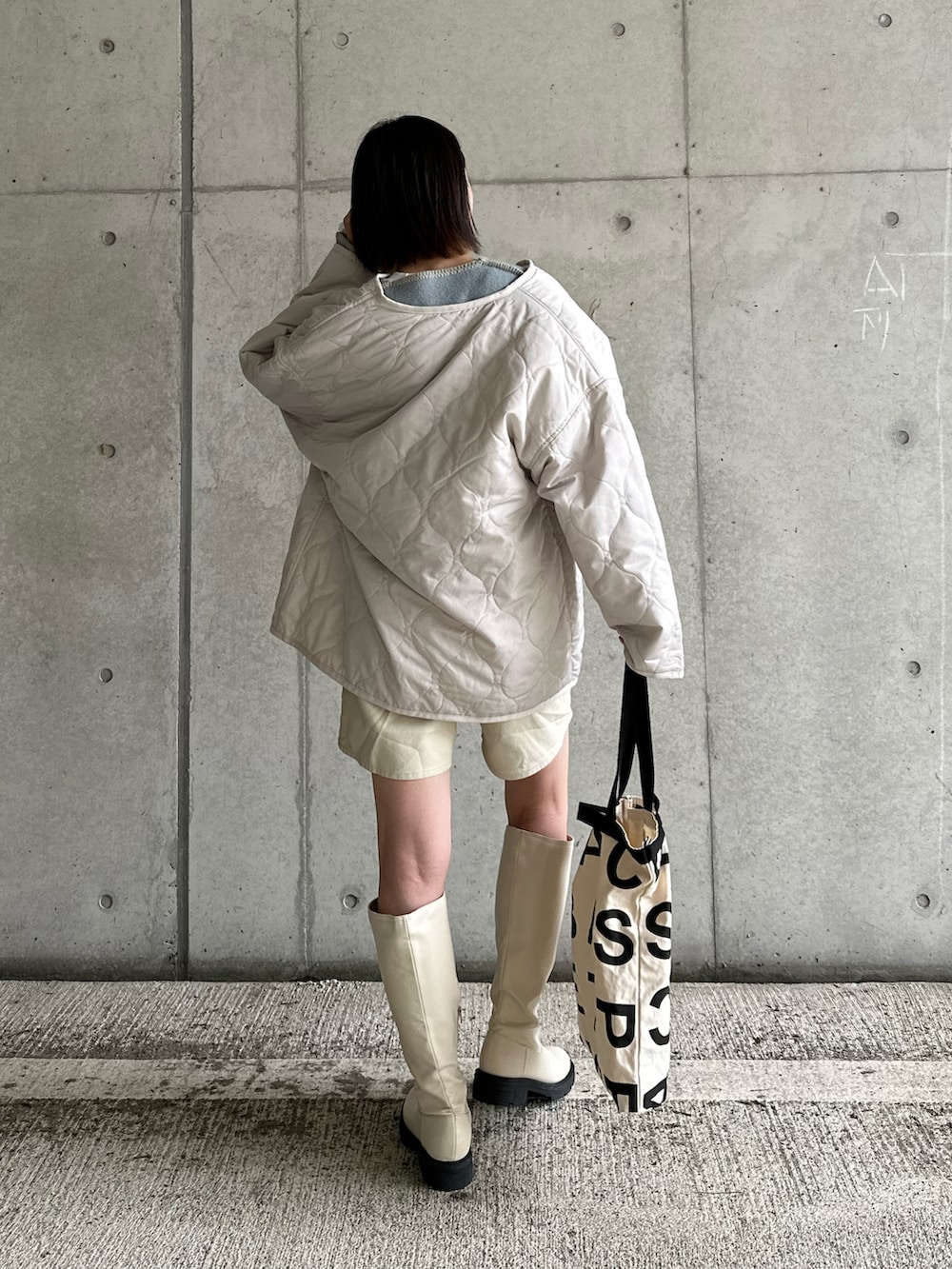 ホワイト系のノーカラージャケット、ブラウン系のベスト、ブルー系のニット/セーターを着用したレディースの冬コーディネートの3枚目の写真