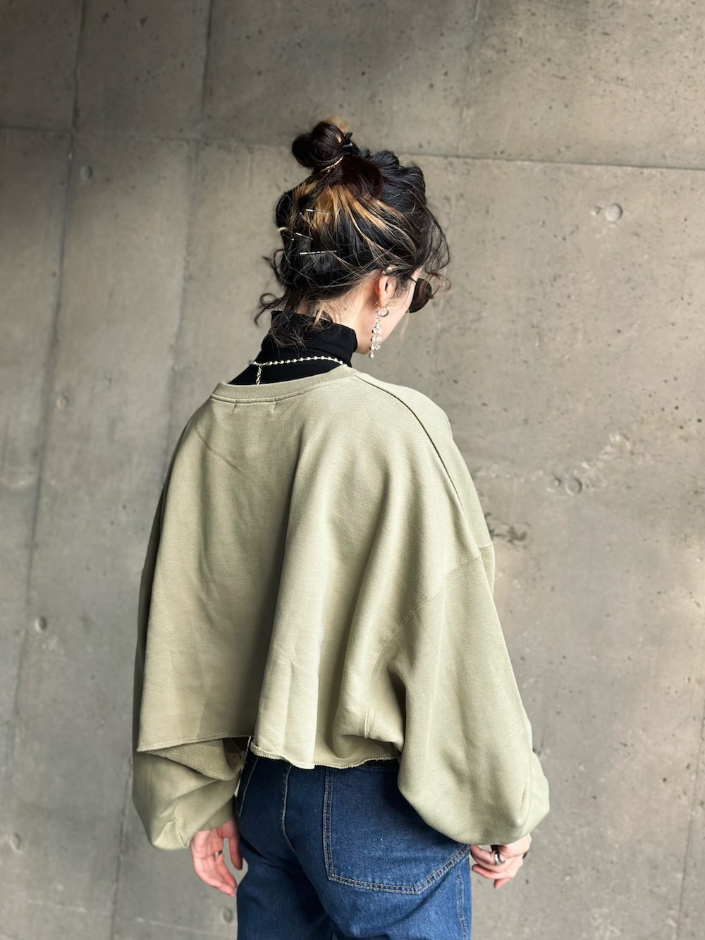 グリーン系のニット/セーター、ブルー系のデニムパンツ、ブラック系のブーツを着用したレディースの冬コーディネートの3枚目の写真