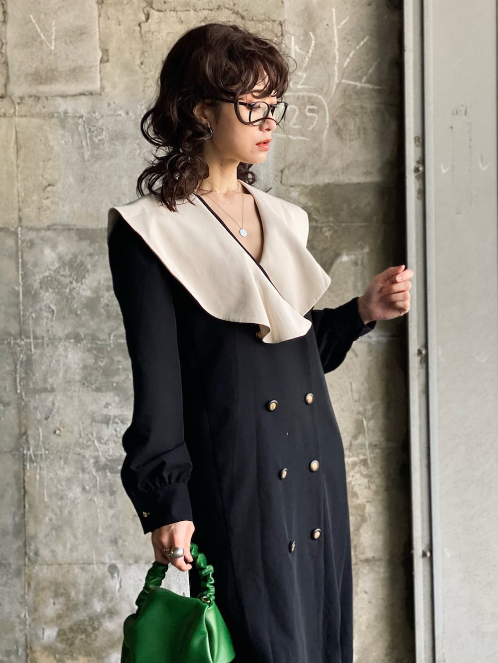 ブラック系のワンピース、グリーン系のハンドバッグ、ブラック系のローファーを着用したレディースの春コーディネートの2枚目の写真