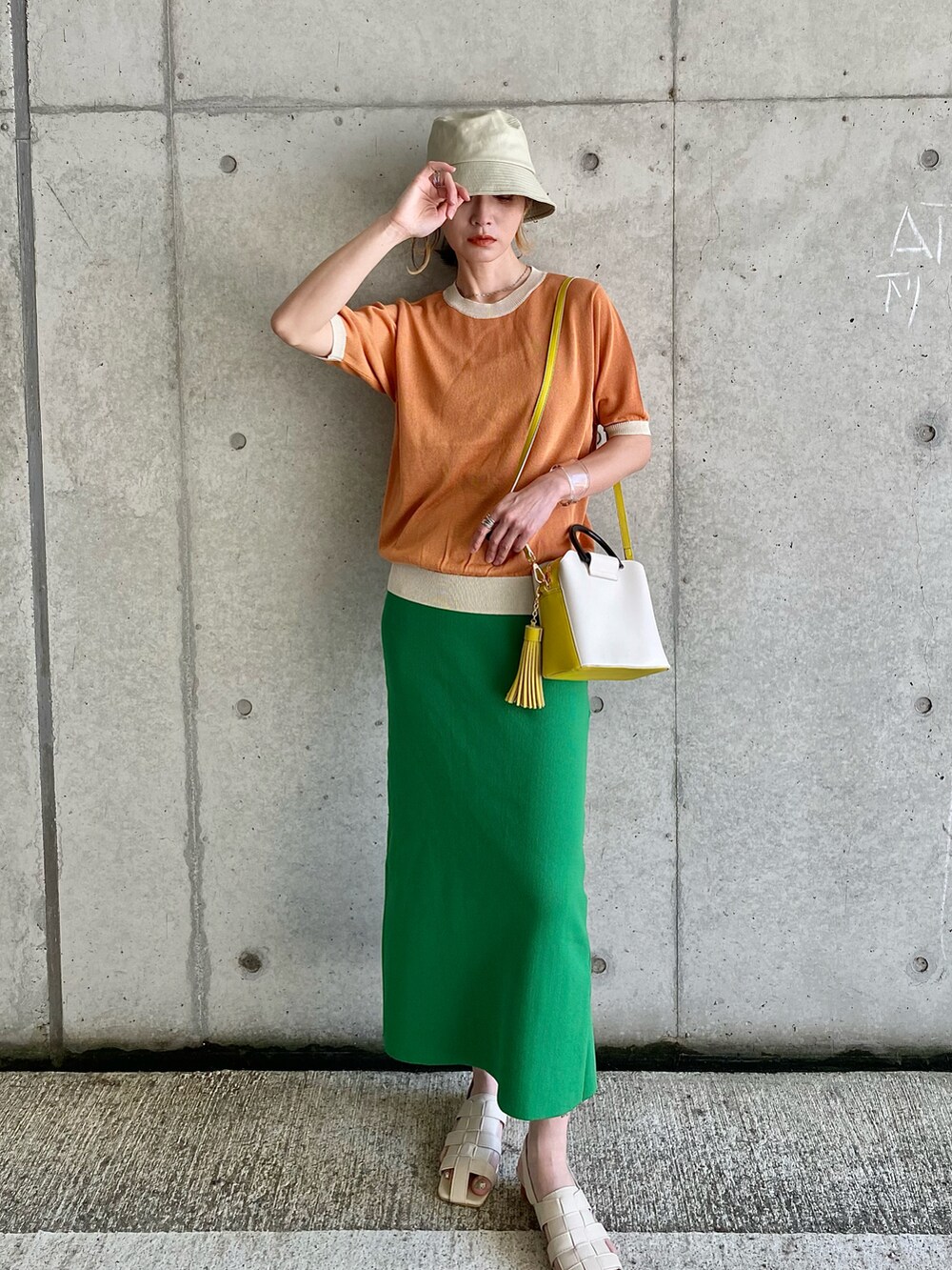 オレンジ系のニット/セーター、ホワイト系のサンダル、ホワイト系のサロペット/オーバーオールを着用したレディースの春コーディネートの3枚目の写真