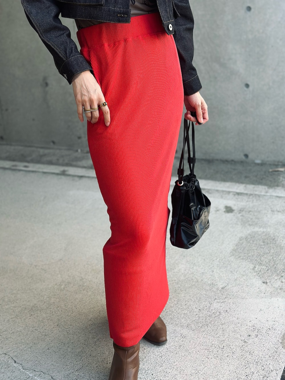 ブラック系のデニムジャケット、レッド系のスカート、ブラック系のハンドバッグを着用したレディースの秋コーディネートの3枚目の写真