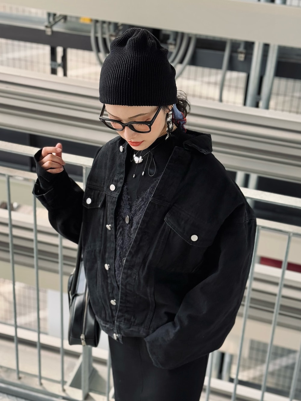 ブラック系のデニムジャケット、ブラック系のワンピース、ブラック系のボストンバッグを着用したレディースの冬コーディネートの2枚目の写真