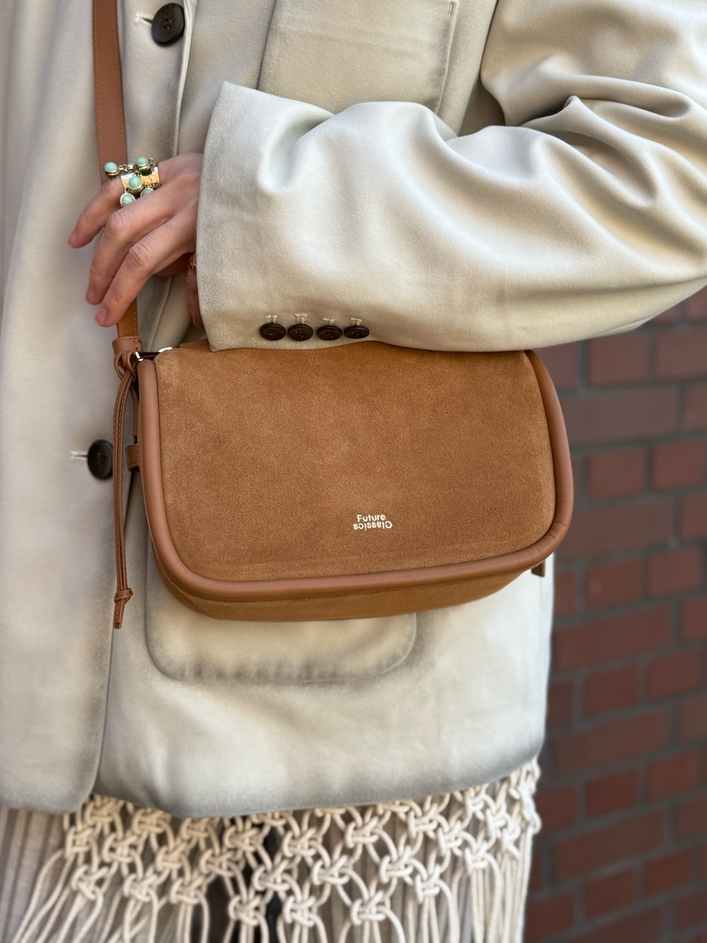 ブラック系のブーツ、グレー系のテーラードジャケット、ブラウン系のショルダーバッグを着用したレディースの冬コーディネートの3枚目の写真