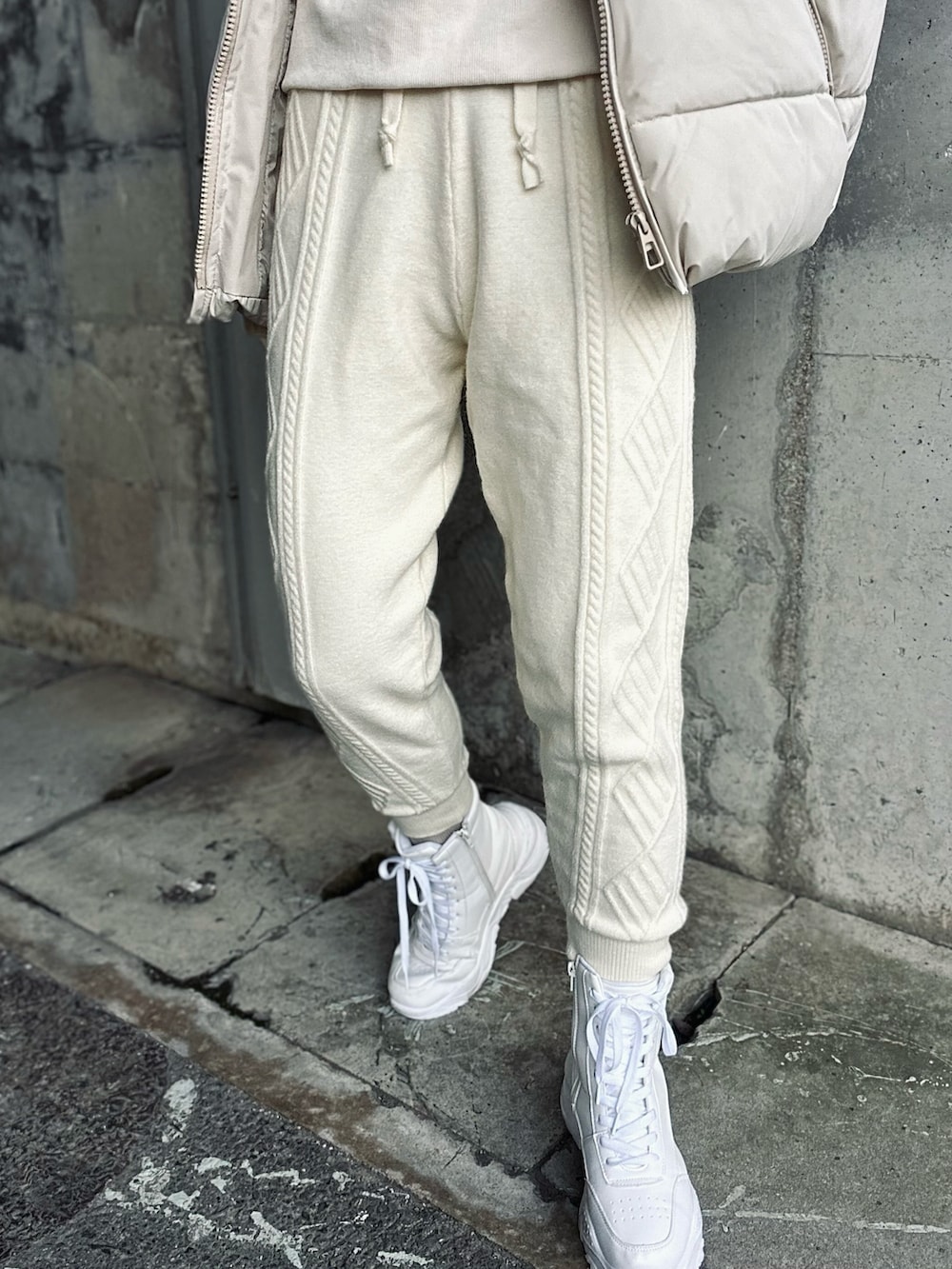 ホワイト系のスウェット、ベージュ系のダウンベスト、ホワイト系のスニーカーを着用したレディースの冬コーディネートの3枚目の写真