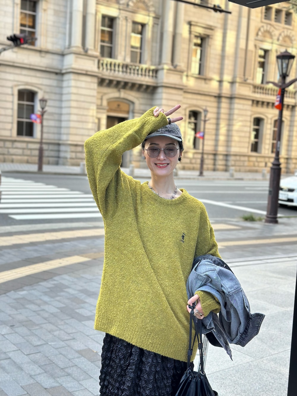 イエロー系のニット/セーター、ブラック系のハンドバッグ、グレー系のスニーカーを着用したレディースの秋コーディネートの4枚目の写真