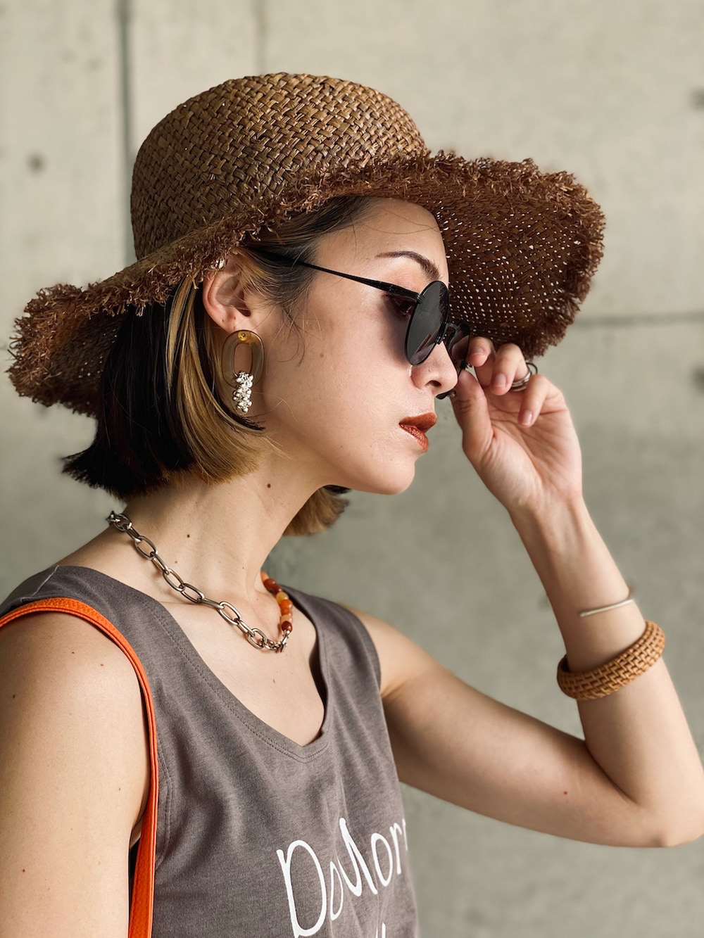 イエロー系のハンドバッグ、ホワイト系のタンクトップ、ブルー系のデニムパンツを着用したレディースの夏コーディネートの4枚目の写真