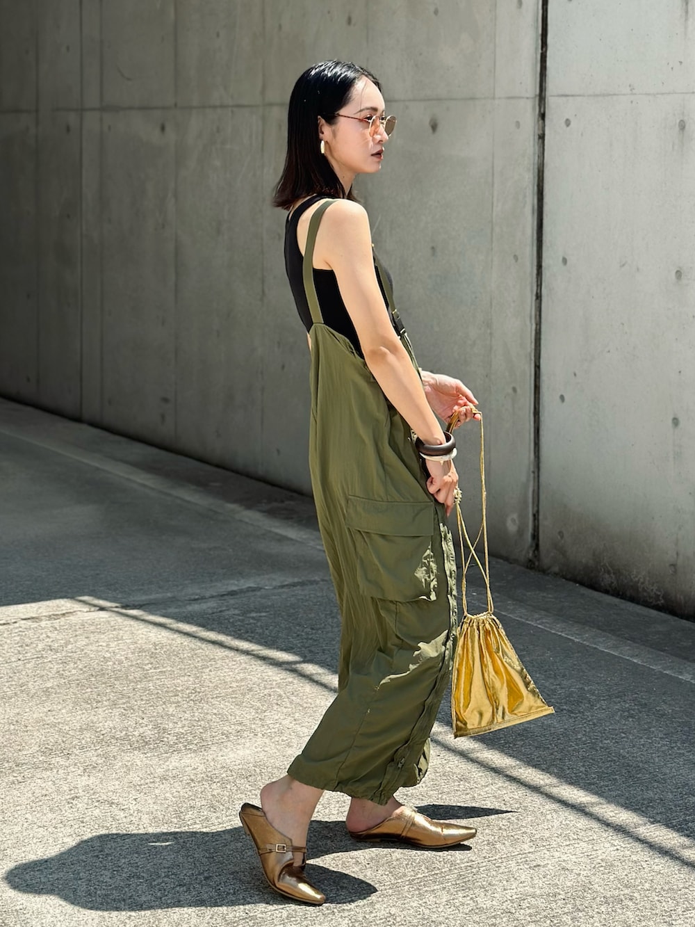 グリーン系のカーゴパンツ、ゴールド系のパンプス、ゴールド系のショルダーバッグを着用したレディースの夏コーディネートの3枚目の写真