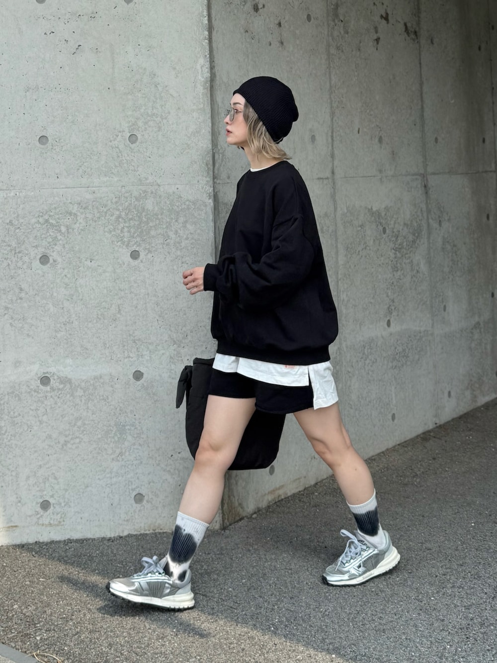 グレー系のスニーカー、グレー系のトートバッグ、ブラック系のセットアップを着用したレディースの秋コーディネートの5枚目の写真