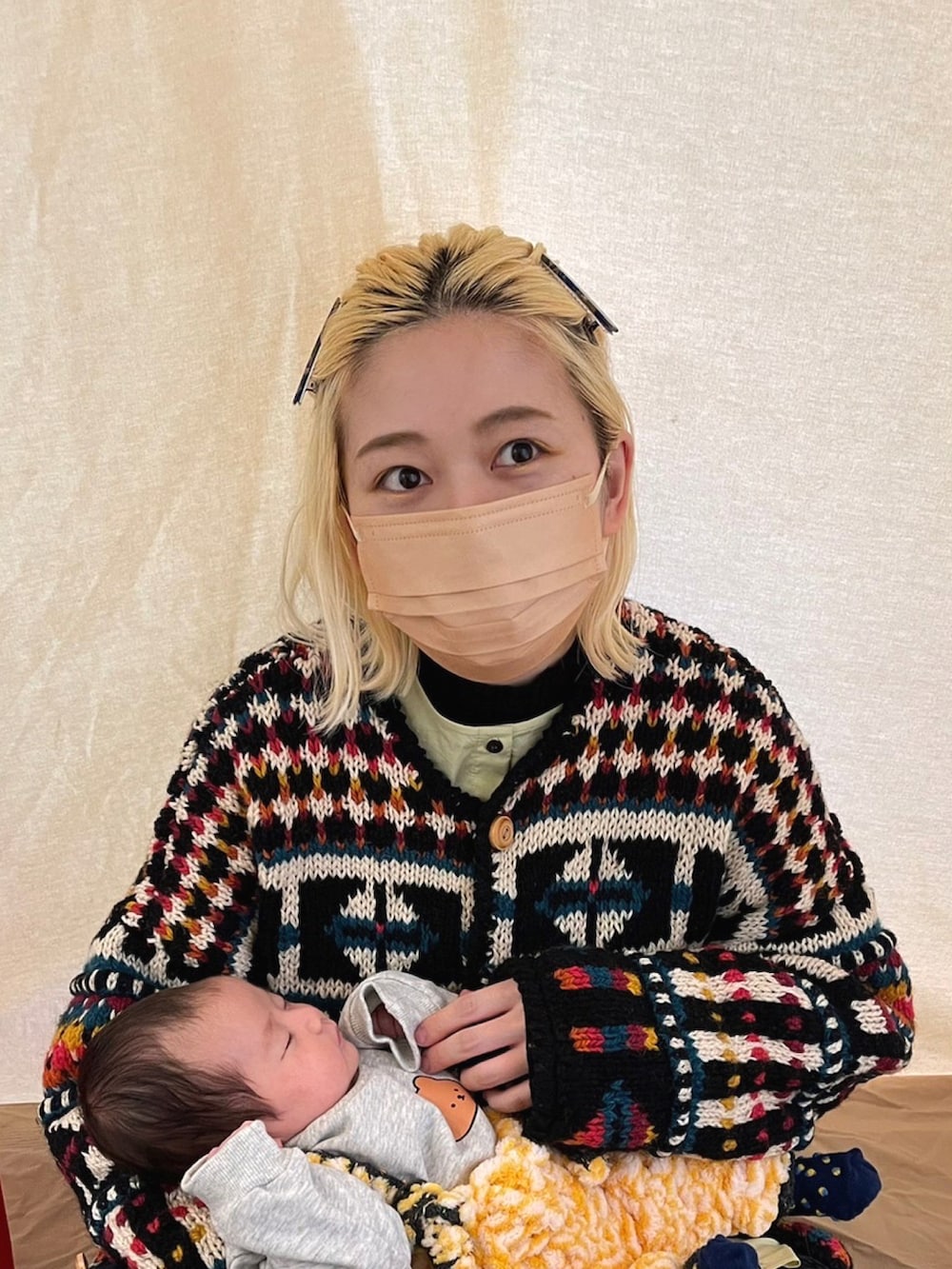 その他のカーディガン/ボレロ、ブラック系のパンツ、レッド系のマザーズバッグを着用したレディースの冬コーディネートの2枚目の写真