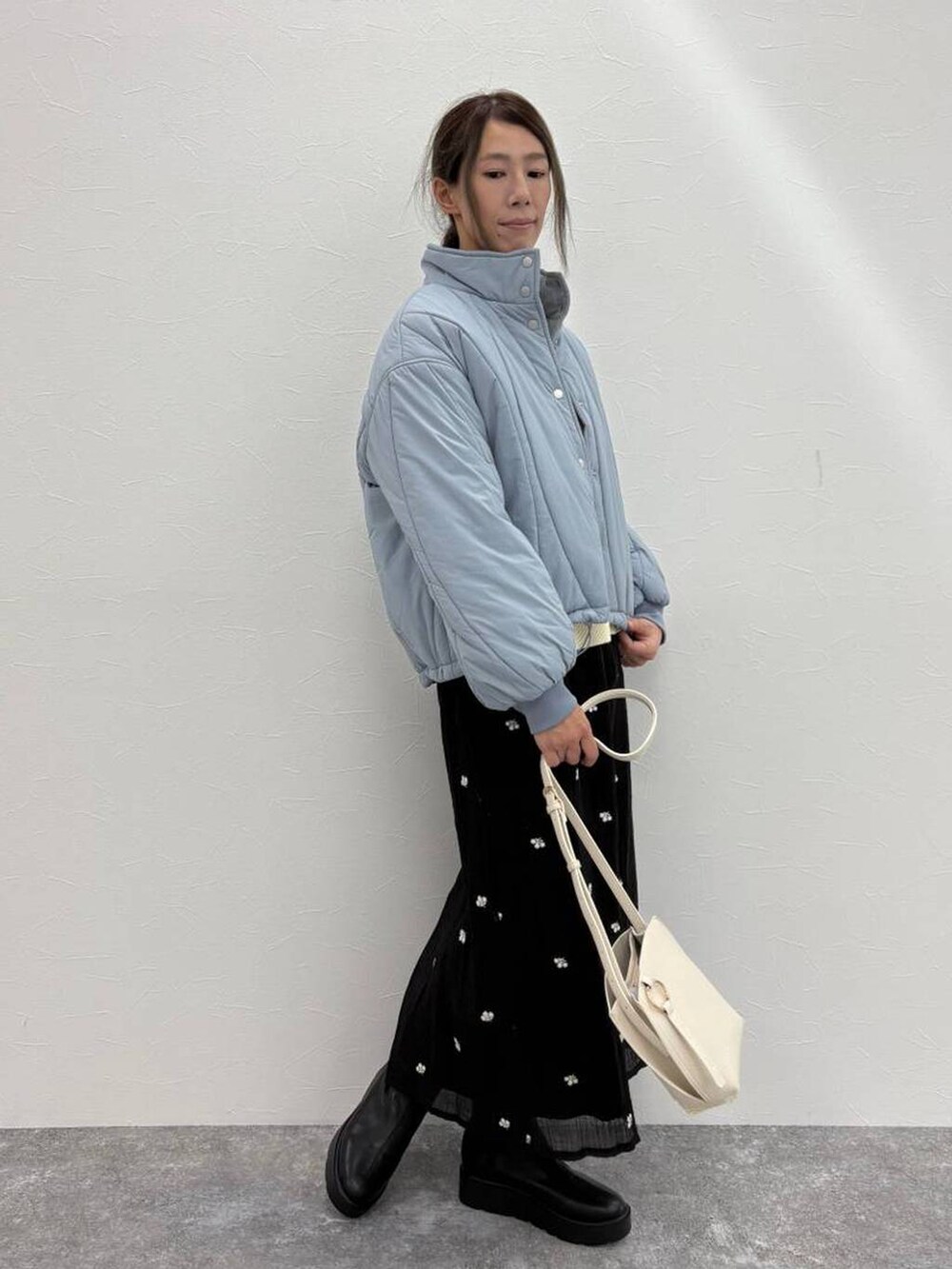 ブラック系のブーツ、ベージュ系のショルダーバッグ、ホワイト系のニット/セーターを着用したレディースの冬コーディネートの3枚目の写真