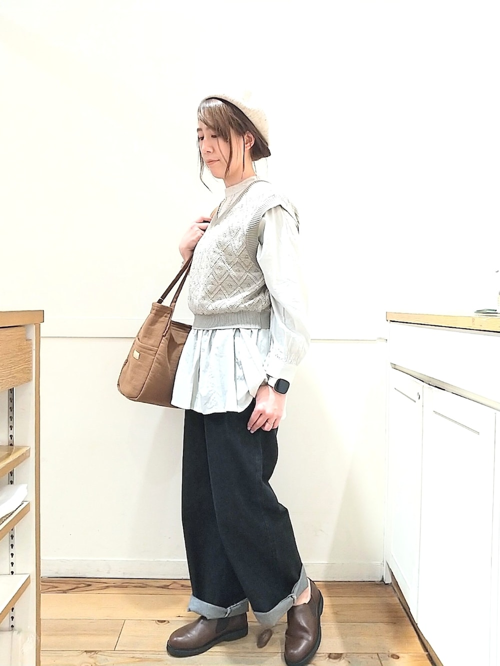 グリーン系のベスト、グレー系のシャツ/ブラウス、ブルー系のトートバッグを着用したレディースの春コーディネートの2枚目の写真