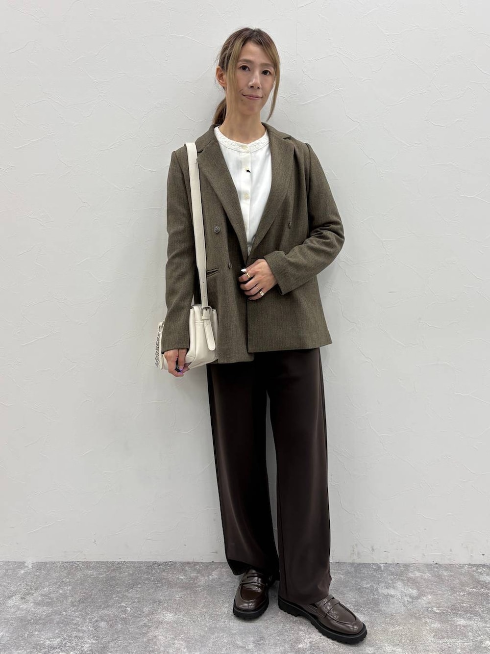 ブラウン系のテーラードジャケット、ホワイト系のシャツ/ブラウス、ブラウン系のローファーを着用したレディースの秋コーディネートの4枚目の写真